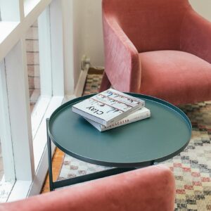 High angle of books placed on small round table near comfortable pink velour armchairs in stylish apartment